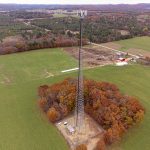 Un pylône de téléphonie mobile en treillis au milieu des champs, vu du ciel