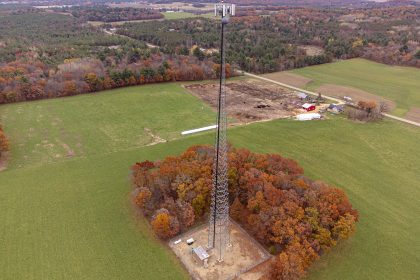 Un pylône de téléphonie mobile en treillis au milieu des champs, vu du ciel
