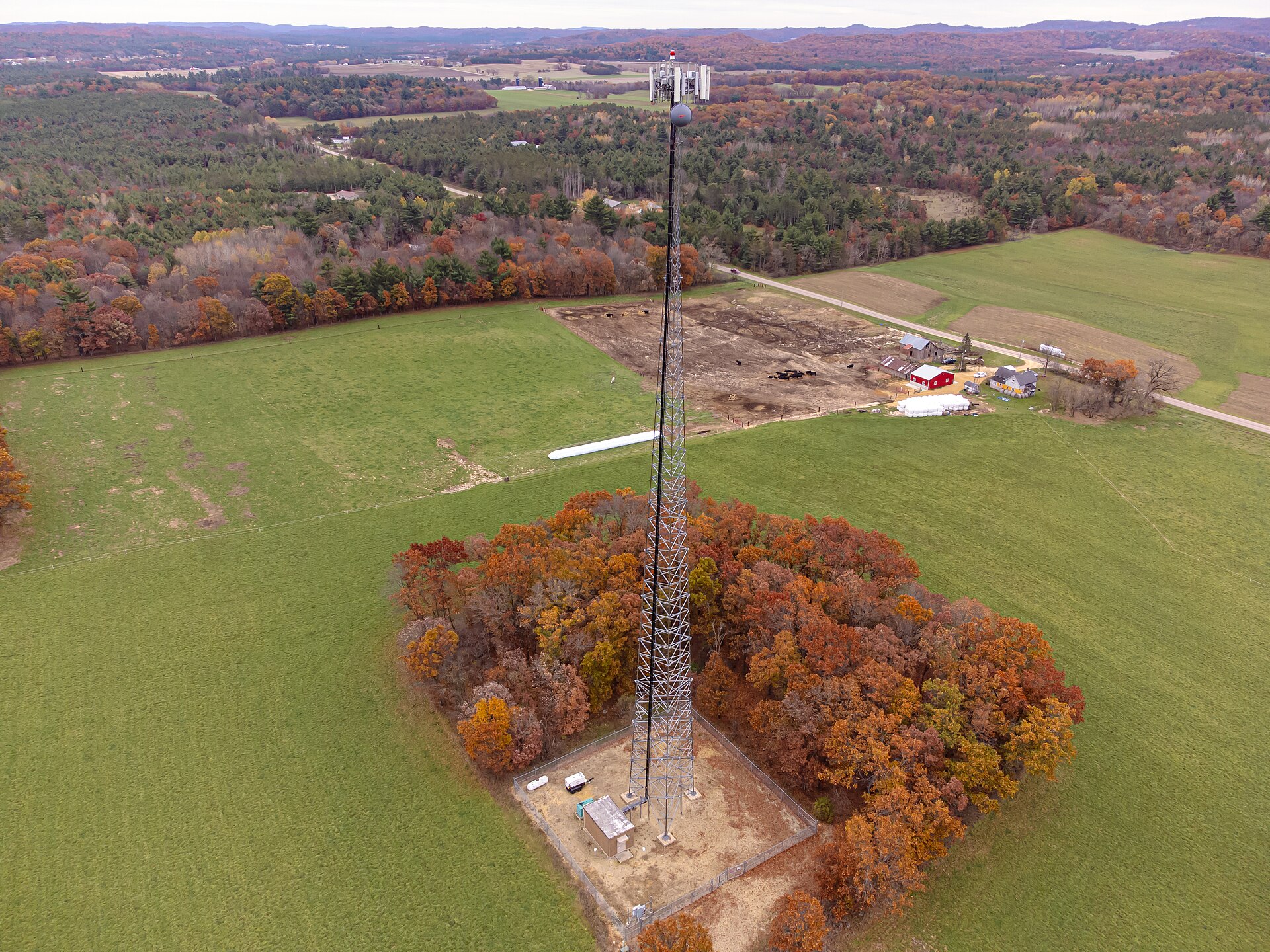 Un pylône de téléphonie mobile en treillis au milieu des champs, vu du ciel